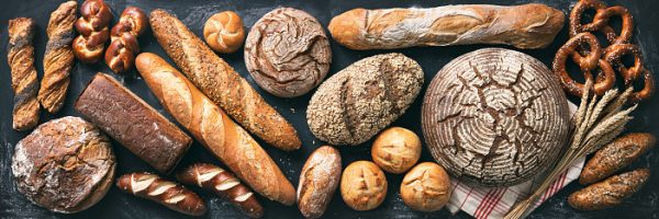 Delicious freshly baked bread assortment on dark rustic background. Top view